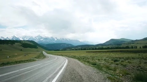 Road in the field on the background of snow-capped mountain peaks. Scene. Alps Vidéo 136453552