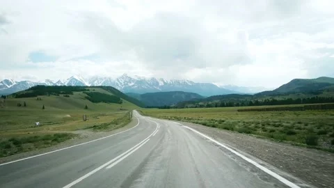Road in the field on the background of snow-capped mountain peaks. Scene. Alps Video stock 136970489