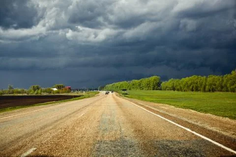 Road in the field with storm clouds Foto stock