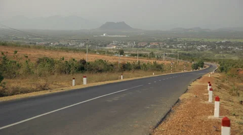 Road in the fields turns to the left. Town and mountains in the background. Stock Footage 37826081
