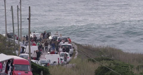 Road filled with walking people near ocean with huge ocean waves, Nazare Stock Footage 157224341