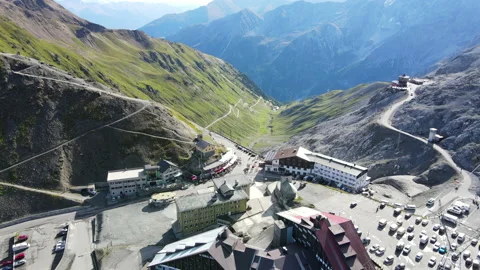 A road full of switchbacks climbing up a mountain towards a cluster of buildings Stock Footage