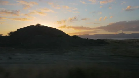 The road goes by at sunset over the ocean, filmed from a car, in New Zealand Stock Footage 220031349