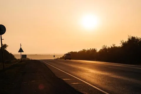 The road going into the distance in the rays of an orange sunset Stock Photos