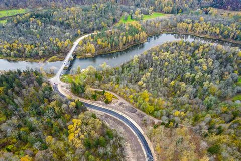 Road intersecting blue river among autumn yellow green forests Stock Photos