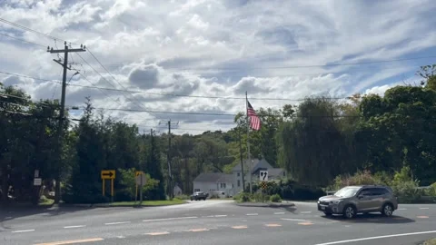 Road Intersection with American Flag Waving and SUV Driving Past Video stock 346261396
