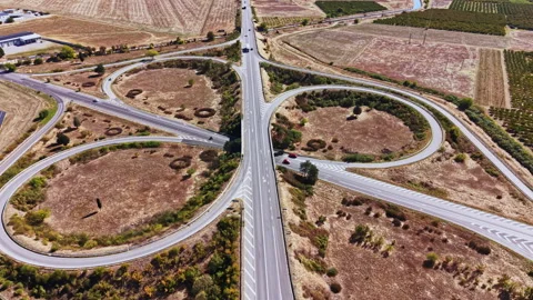 Road intersection with circular roundabouts in a rural area surrounded by fields Video stock 347749237