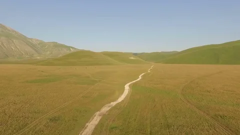 A road in a large valley surrounded by mountains. Aerial video. About farming Stock Footage 70354366