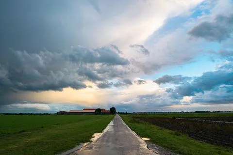 Road leading to massive storm cloud over a farm Stock Photos