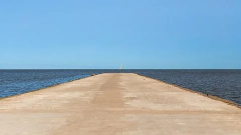 Road leading to the sea to the horizon. Sailboat on the horizon. Stock Photos