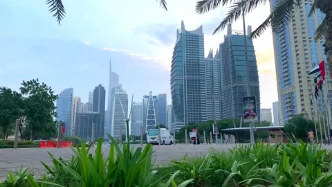 Road with light traffic in JLT at sunset through green foliage with waving flags Stock Footage 150616227