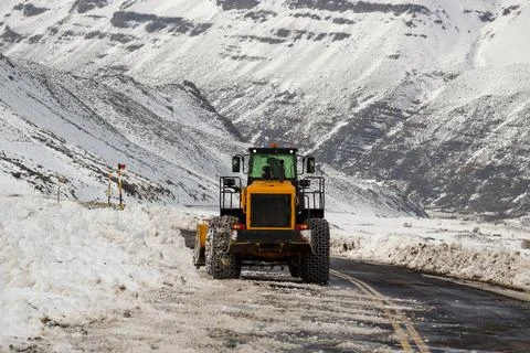 Road machine with chains, removing snow. Stock Photos