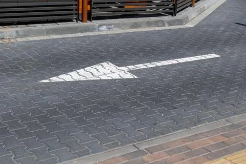 Road marking pointing forward on a gray pavement in a city near a parking a.. Stock-Fotos
