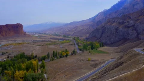 A road in the middle of mountains with trees along Stock Footage 166159048