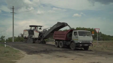 A road milling machine cuts off old asphalt and loads it into a van Stock Footage 145466031
