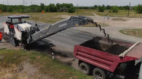 A road milling machine cuts old asphalt and loads it into a dump truck. Stock Footage 145466087