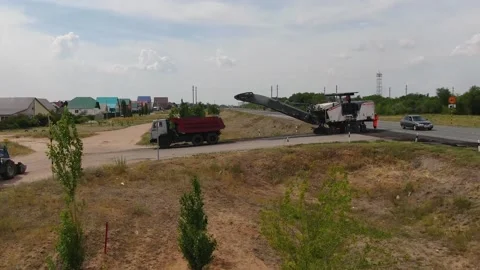A road milling machine cuts old asphalt and loads it into a dump truck. Stock Footage 145466089