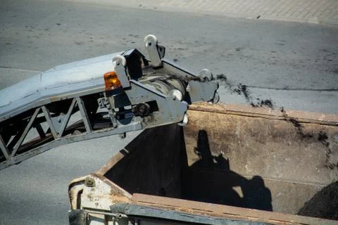 Road milling machine is loading the truck by asphalt powder. Removing old pav Stock Photos