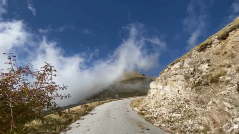 Road at the mountain and fast moving clouds, point of view. Video stock 142734783