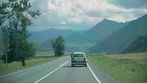 Road in a mountain valley. View from the car. Ahead is a string of cars 스톡 동영상 160653173