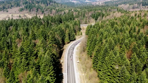A road in a mountainous area. A group of cyclists is moving along the track Stock Footage 204076925