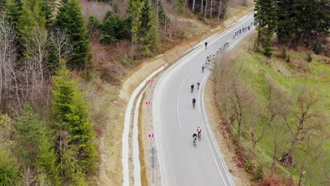 A road in a mountainous area. A group of cyclists is moving along the track Stock Footage 209262861