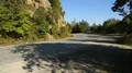 Road in mountains, high cliff with trees on it standing at shoulder, nature HD Footage