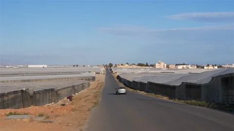 A Road With A Passing Car Through A Large Group Of Greenhouses Stock Footage 230095170