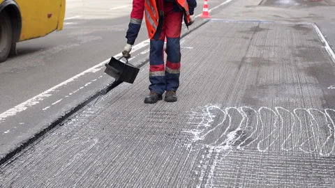 Road repair. Work details, workers pour resin road surface to cover the asphalt. Stock Footage 119945645