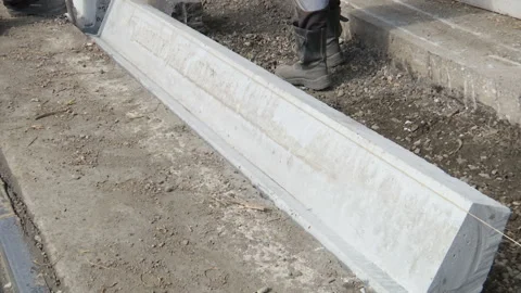 Road repairs. City workers lay a curb stone in the trench. Stock Footage 131958853