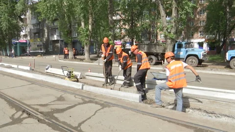 Road repairs. City workers lay a curb stone in the trench. Stock Footage 131959060