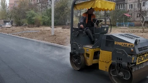 Road roller compacting fresh asphalt on new street path in residential distri Stock Footage 339802460