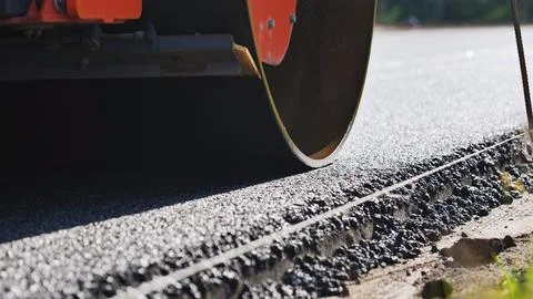Road roller compacting fresh asphalt during new highway construction Stock Photos