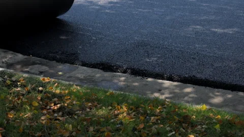 Road roller, steamroller in action, pressing down freshly laid asphalt on a new Stock Footage 310430885