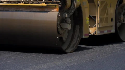 Road roller , steamroller in action, pressing down freshly laid asphalt on a Stock Footage 310432127