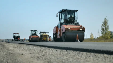 Road rollers level and compact the asphalt against the blue sky. A layer of Stock Footage 140104709