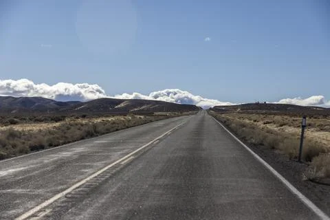 Road runs through empty desert and sagebrush heading toward the mountains Stock Photos