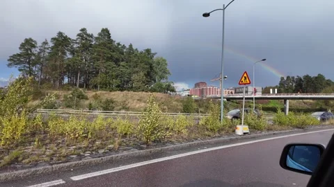 Road Scene from a Vehicle with Rainbow and Construction Signs Stockbeeldmateriaal 347683353