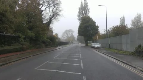 Road with security fence, tower block  demolition, in distance car turns Stock Footage 14783905