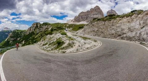 Road with a sharp turn in the mountains with cyclist Stock Photos