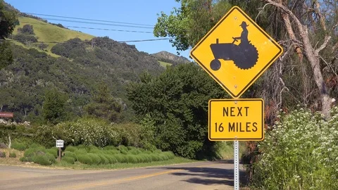 Road sign indicates there are farmers with tractors for the next 16 miles in Stockbeeldmateriaal 141843655