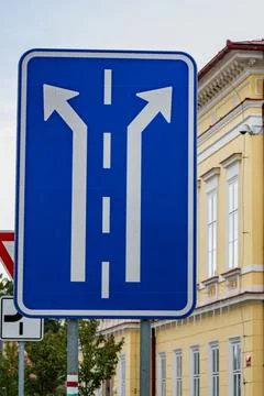 Road sign indicating two direction choices in Czechia with a yellow building in Stock Photos