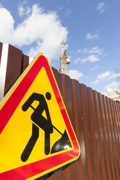 Road sign for repairs installed on a metal fence 写真素材