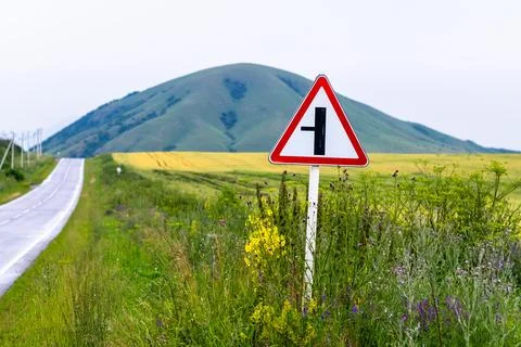 Road sign warning of an intersection with a minor road Stock Photos