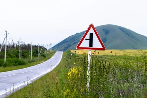 Road sign warning of an intersection with a minor road Stock Photos