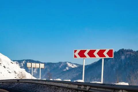 Road sign warning of a sharp and dangerous turn to the left with red arrows o Stock Photos