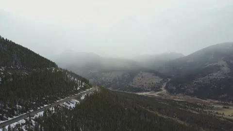A road sits on the side of a snowy mountain with a foggy landscape behind Video stock 167675953