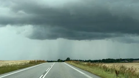 Road stretches towards dark storm clouds with distant rain showers. 스톡 동영상 343300570