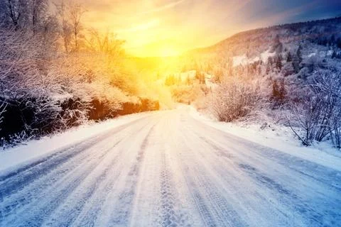 Road to the sunset in the winter mountains Stock Photos