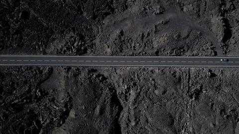 The road  is surrounded by black volcanic lava. Top view. Minimalistic landscape Stock Footage 101053886